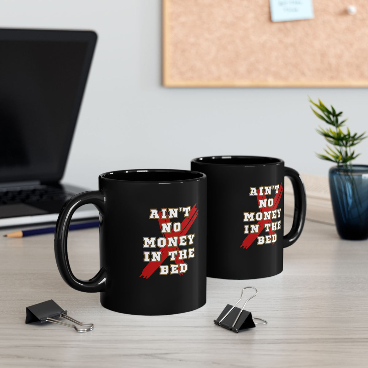 Black coffee mug held in hand showing the Ain't No Money in the Bed print